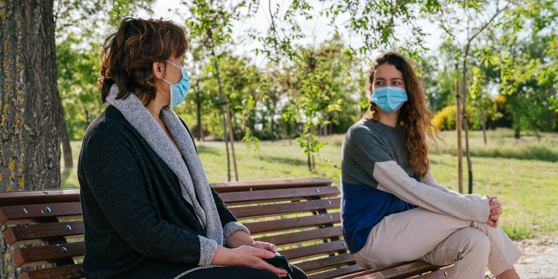 Two women wearing masks social distancing talking