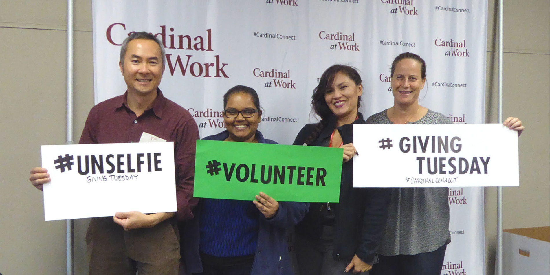 4 employees volunteering for Giving Tuesday, posing with #volunteer signs