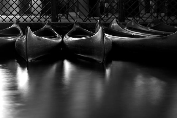 Black and white photo of boats along a pier