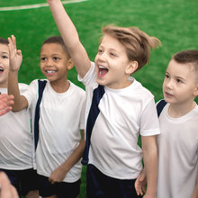 Group of young boys excitedly raising their hands