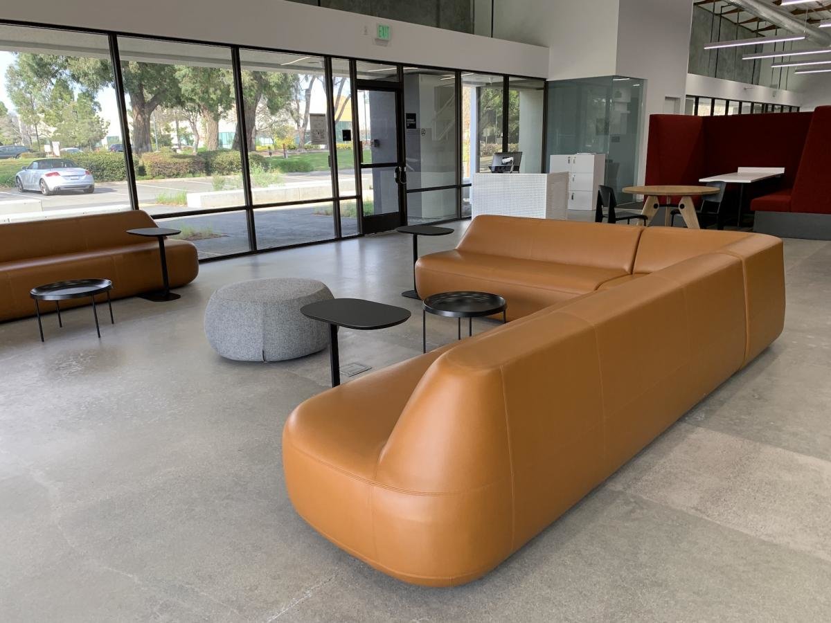 Large camel colored L-shaped couch in a lobby