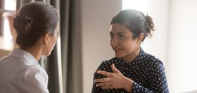 Serious Indian mentor worker talk to female colleague teach intern